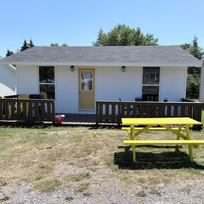 White cabin with a yellow door at Doyle's Landing, across from Northern Bay Sands
